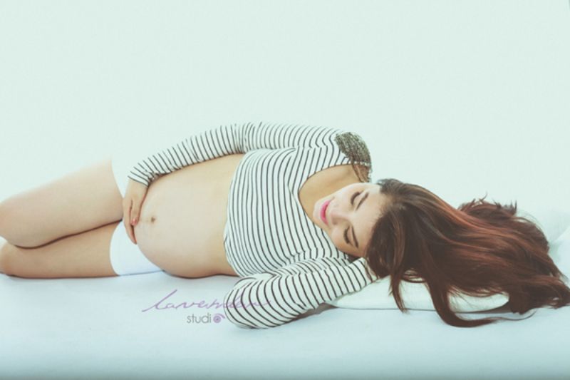 người mang thai ddnag nằm nghiêng trên sàn